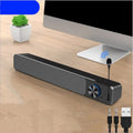 Black and white desktop computer speaker with 2.0 channel audio on wooden desk