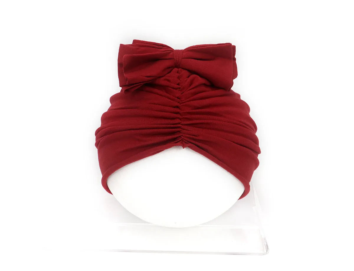 Soft acrylic knitted baby hat in a solid colour, shown stretched to demonstrate fit.