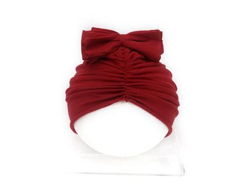 Soft acrylic knitted baby hat in a solid colour, shown stretched to demonstrate fit.