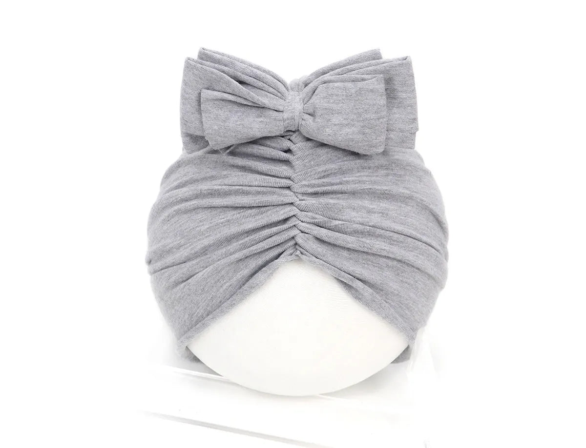 Soft acrylic knitted baby hat in a solid colour, shown stretched to demonstrate fit.
