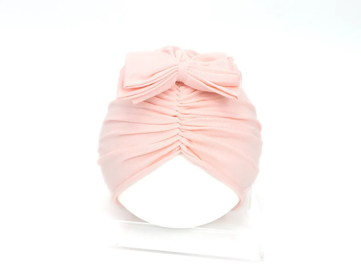 Soft acrylic knitted baby hat in a solid colour, shown stretched to demonstrate fit.