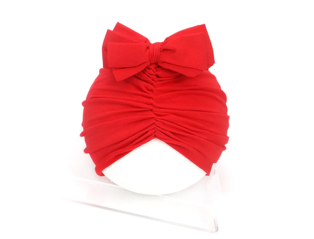 Soft acrylic knitted baby hat in a solid colour, shown stretched to demonstrate fit.
