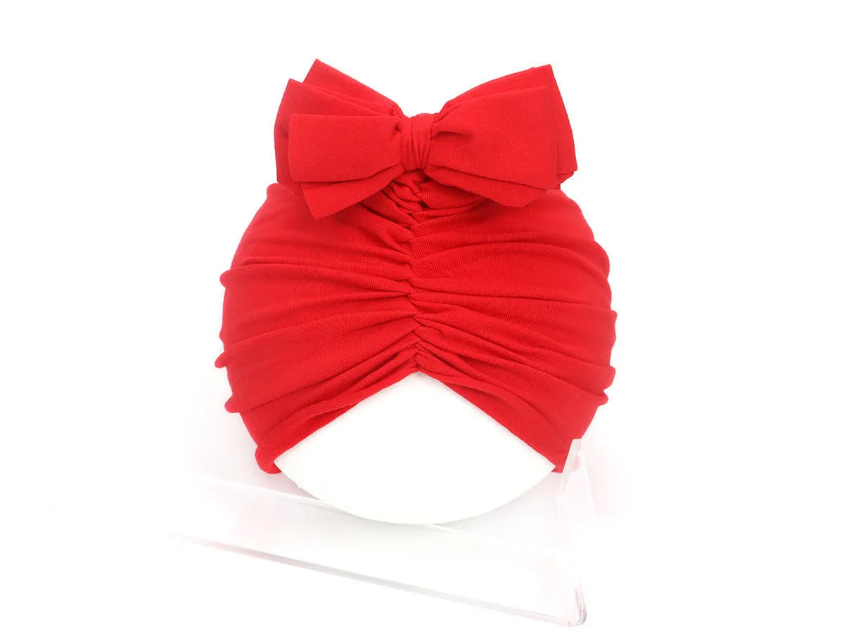 Soft acrylic knitted baby hat in a solid colour, shown stretched to demonstrate fit.