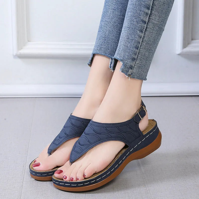Women's black casual wedge heel flip flop sandals showing adjustable back buckle strap and solid colour design.