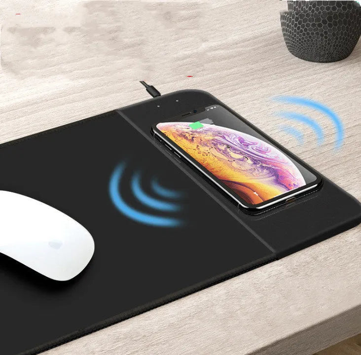 Black wireless charging mouse pad with cartoon design, RGB edge lighting, and non-slip rubber base.