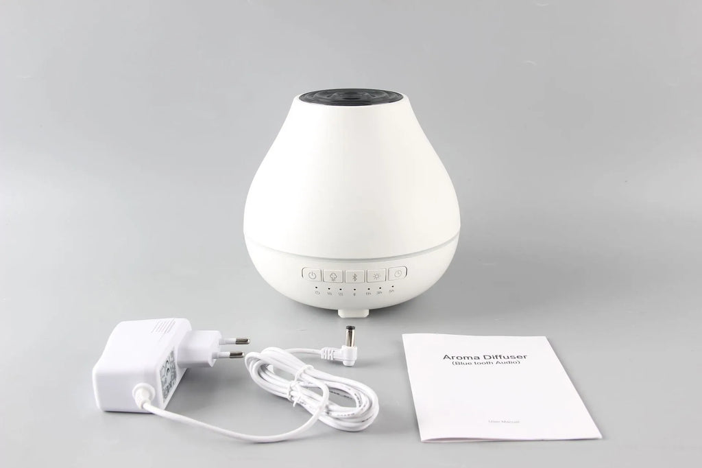 White circular Bluetooth humidifier and aroma diffuser with single mist outlet on a table