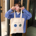 Women's orange geometric print canvas tote bag with zipper closure and shoulder straps.