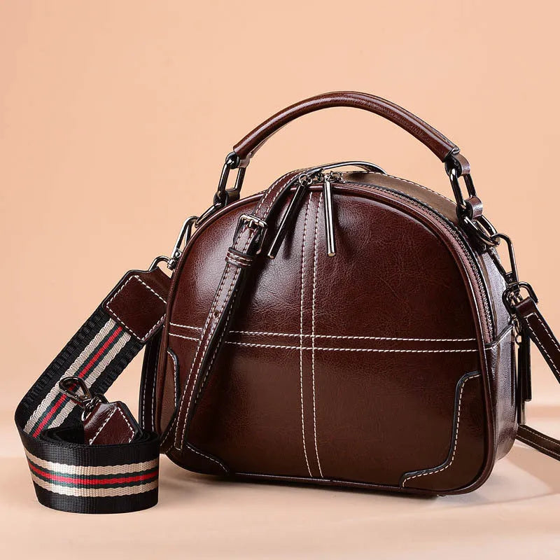 Simple round leather women's handbag with soft double handles and a zipper opening