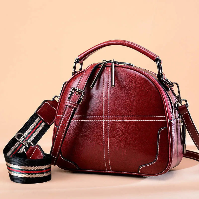 Simple round leather women's handbag with soft double handles and a zipper opening