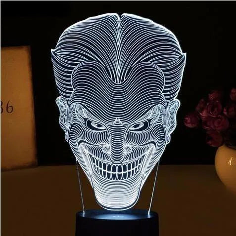 A clear acrylic 3D LED table lamp displaying gradient colours, standing on a square base with a USB cable and remote control.