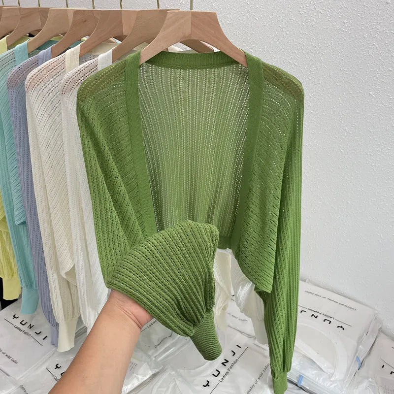 Thin loose linen blouse with hollow out lantern sleeves in apricot colour on a hanger.