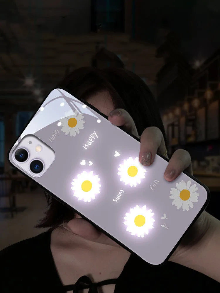 White luminous iPhone case with purple daisy design and voice-activated colour light on a table.