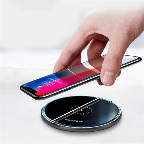 Black 15W fast wireless charging pad with LED indicator light on a desk