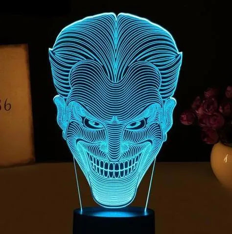 A clear acrylic 3D LED table lamp displaying gradient colours, standing on a square base with a USB cable and remote control.
