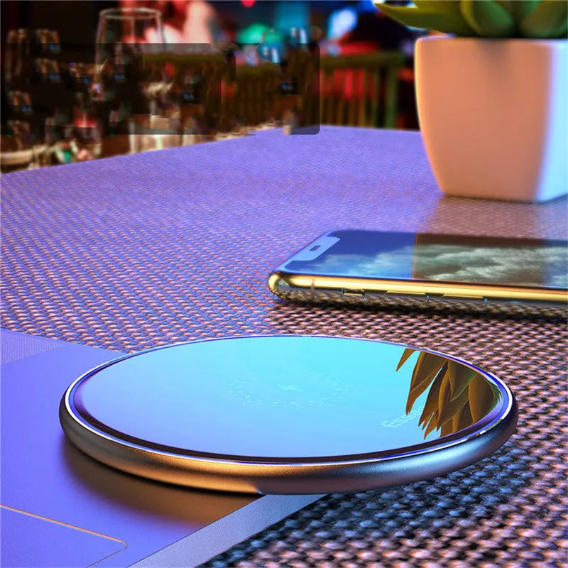 Black 15W fast wireless charging pad with LED indicator light on a desk