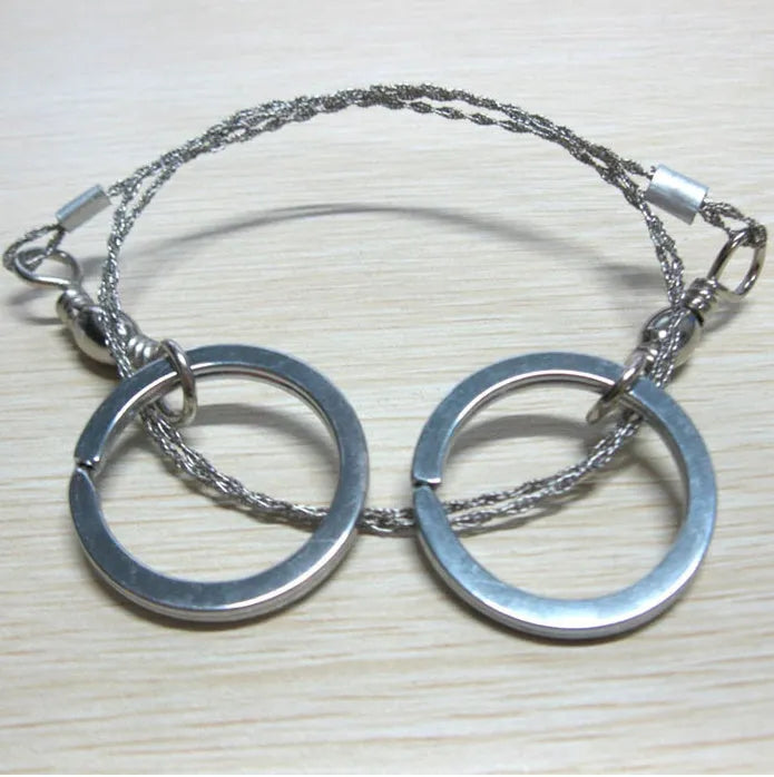 55cm stainless steel survival wire saw with pull rings and hoops on a green background.