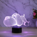 Dog-shaped 3D desktop lamp glowing in multiple colours on a wooden surface.
