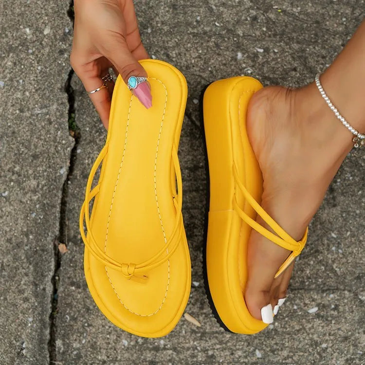 Thick rubber sole flip-flops in multiple colours on a beach background.