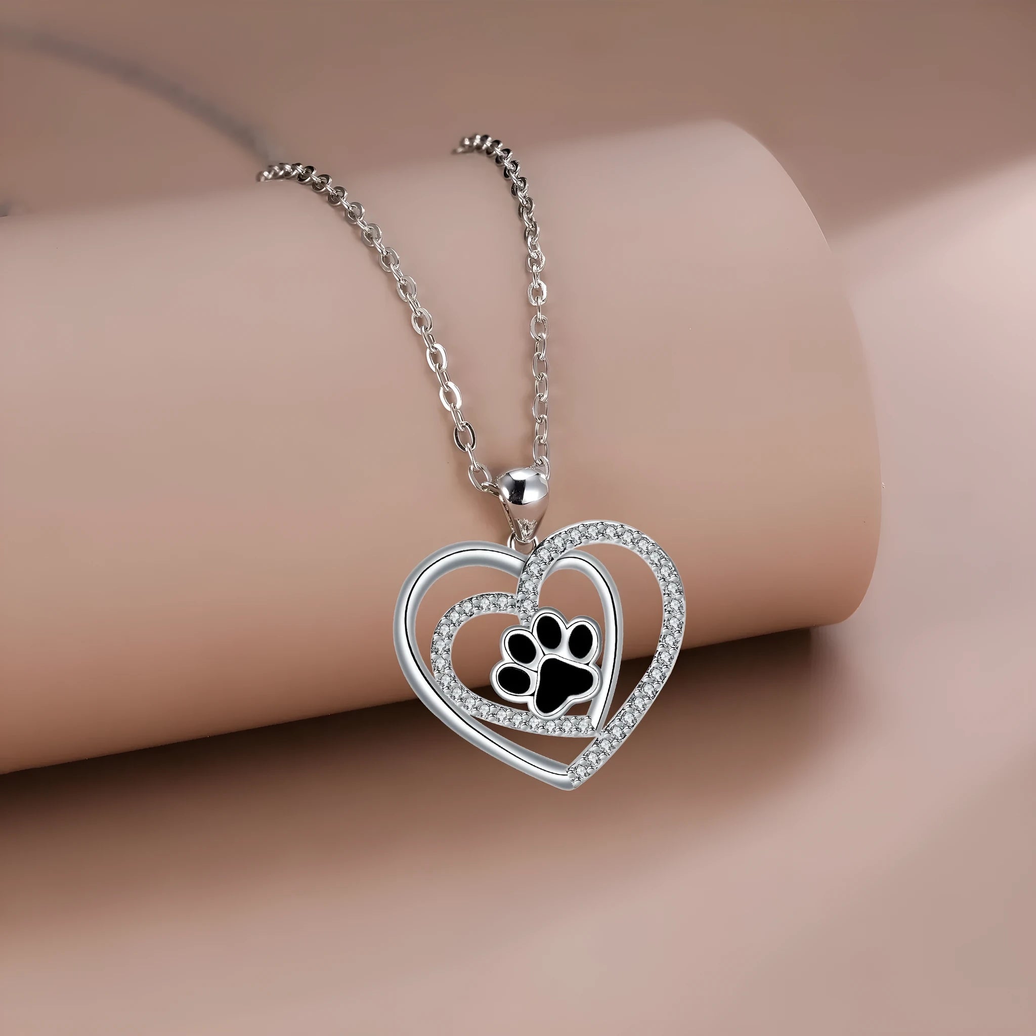 Close-up of a women's heart-shaped copper necklace with a detailed dog paw print pendant on a cross chain.