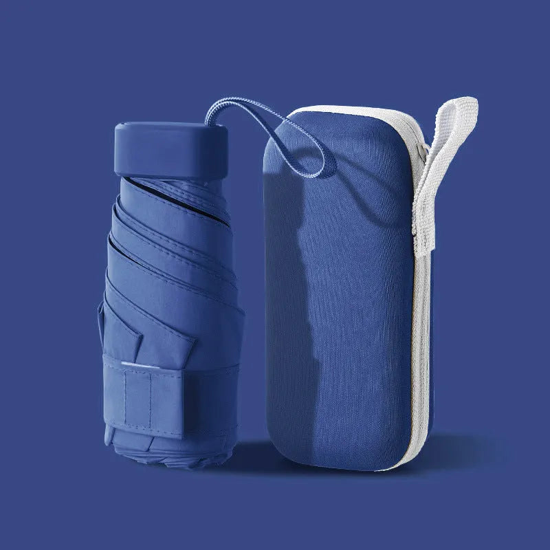 A folded six-fold flat umbrella in a capsule box, showing the steel ribs and rubber handle.