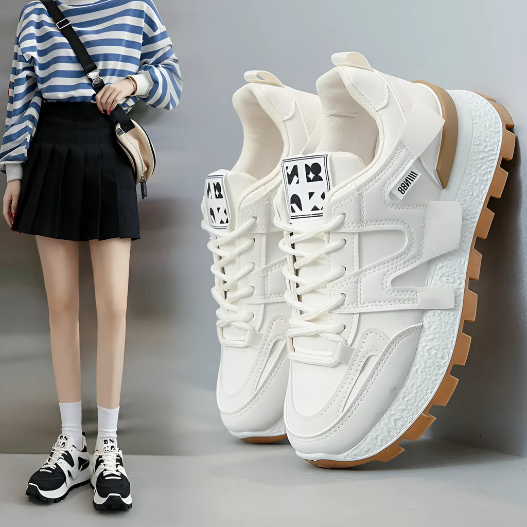 A pair of low-top black or white sneakers with a round toe, lace-up front, and flat rubber sole.