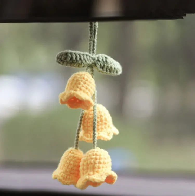 Green and white knitted wool car plant decoration with white hanging rope.