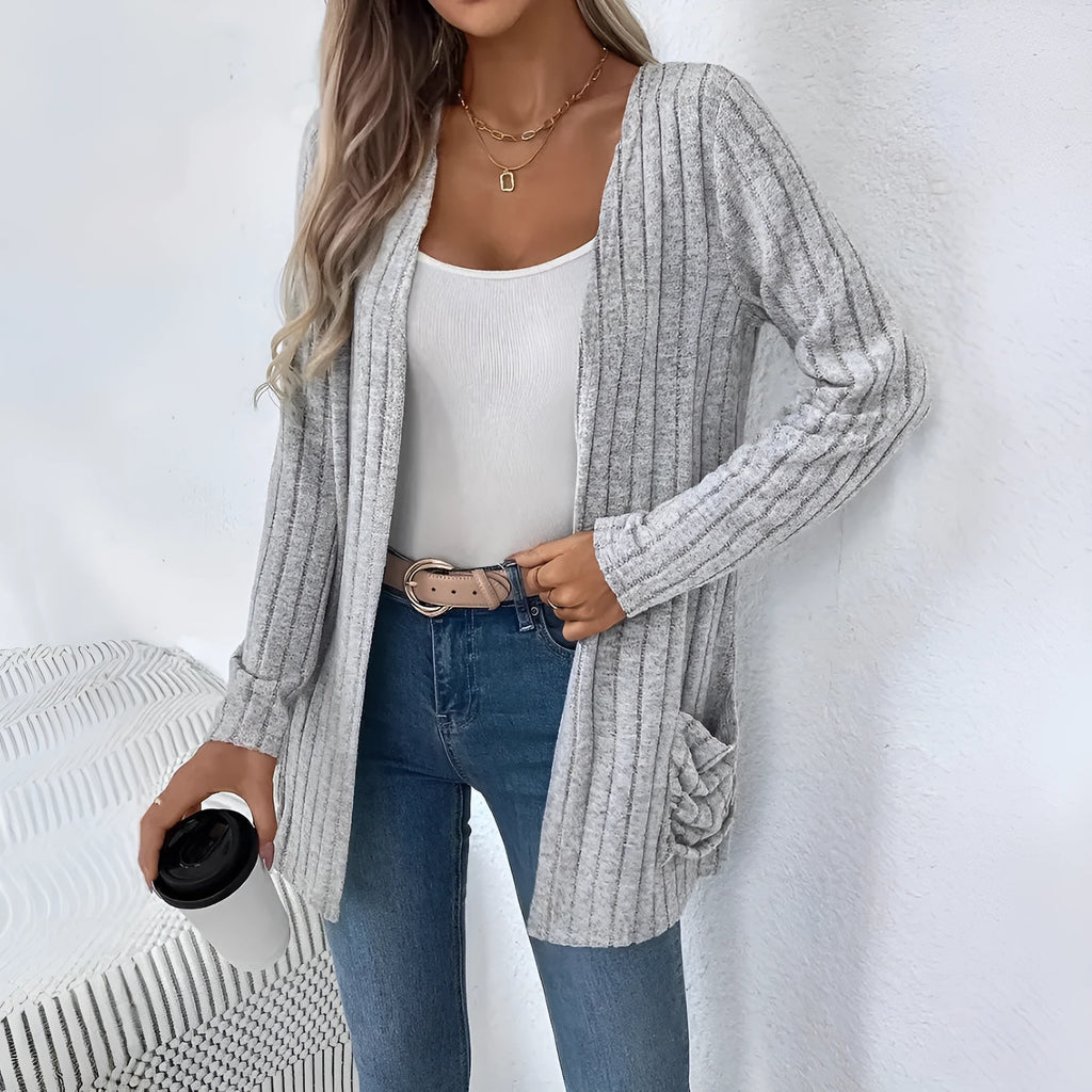 A grey loose fit long sleeve cardigan with pockets hanging on a hanger.