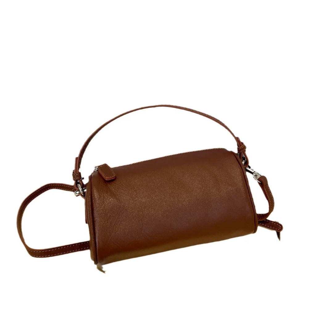 Soft vegetable-tanned leather crossbody phone bag in cylindrical shape with adjustable strap.