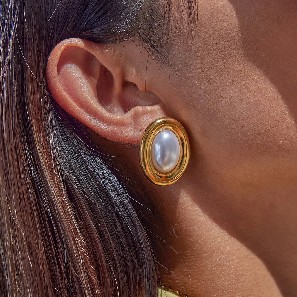 A pair of stainless steel stud earrings for women featuring a single vintage pearl, with butterfly clutch backings visible.