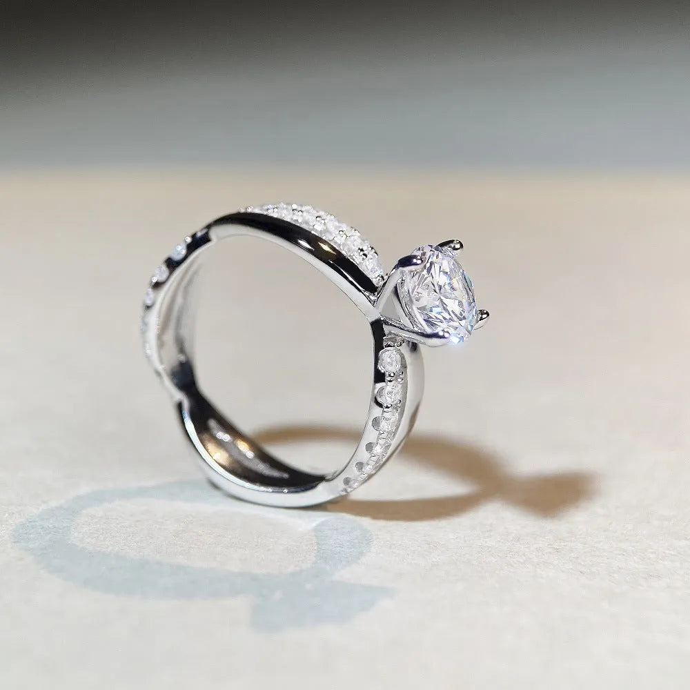 Silver moissanite ring with twisted arm band and four-claw setting holding 1 karat stone