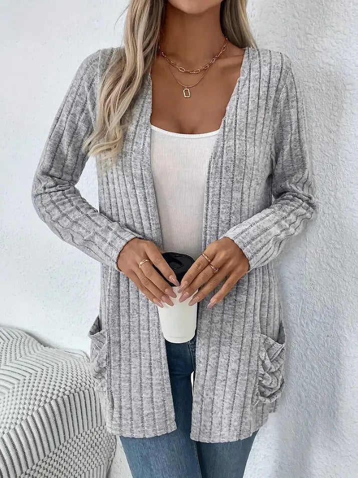 A grey loose fit long sleeve cardigan with pockets hanging on a hanger.