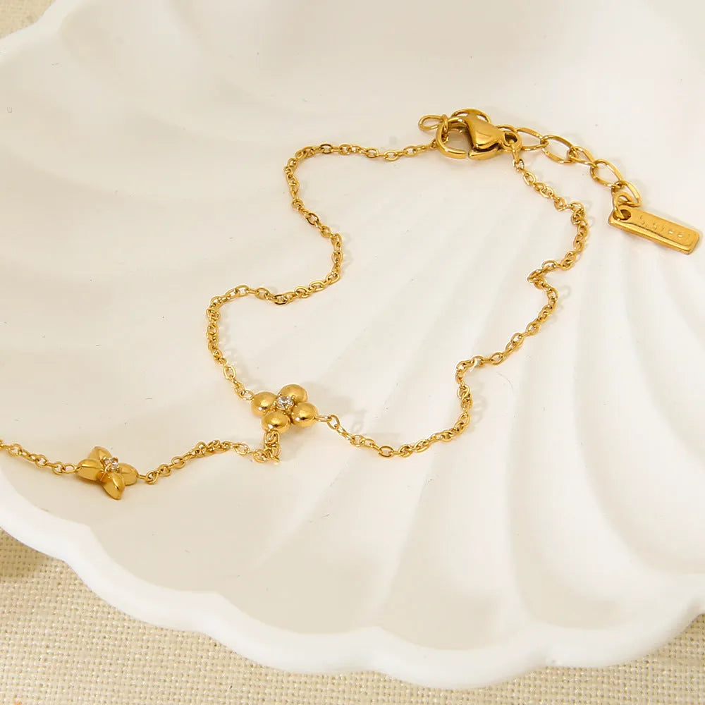 Gold stainless steel women's bracelet with geometric shape, flower and eight-pointed star details.