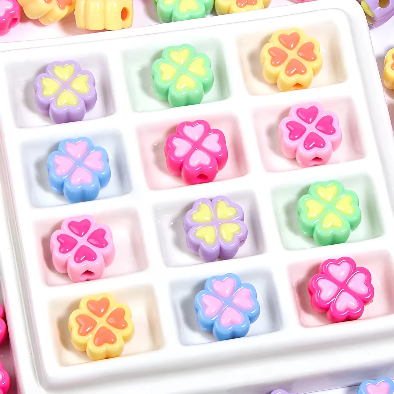 A pile of 15mm frosted acrylic four-leaf clover beads in mixed colours including pink, green, and blue.