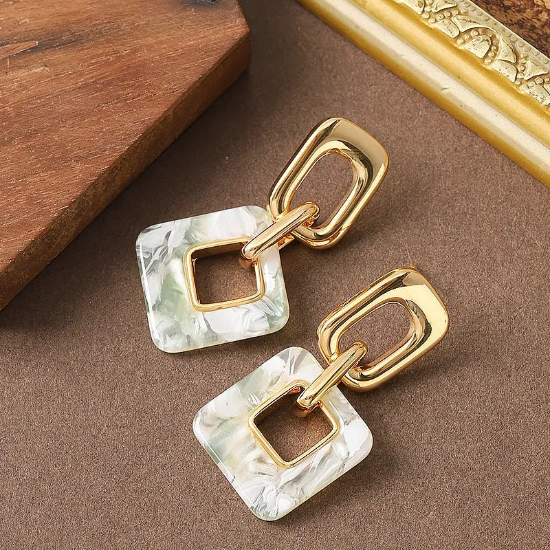 A pair of hollow geometric square copper earrings with a chamfered pattern design.