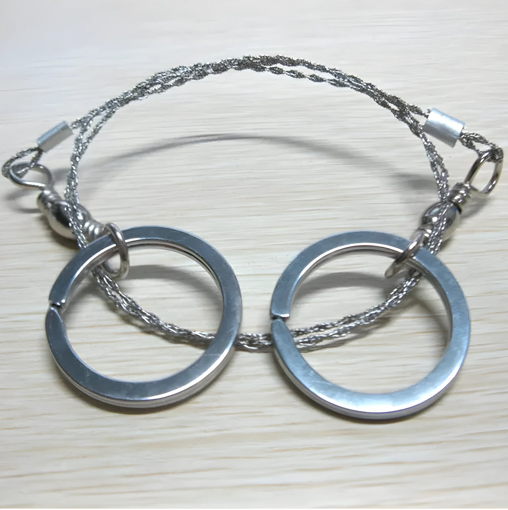 55cm stainless steel survival wire saw with pull rings and hoops on a green background.