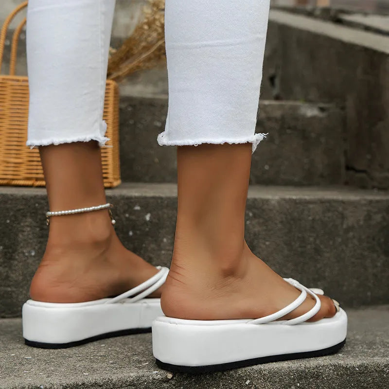 Thick rubber sole flip-flops in multiple colours on a beach background.