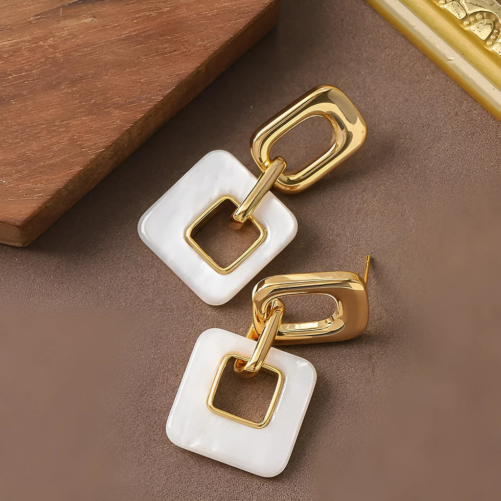 A pair of hollow geometric square copper earrings with a chamfered pattern design.