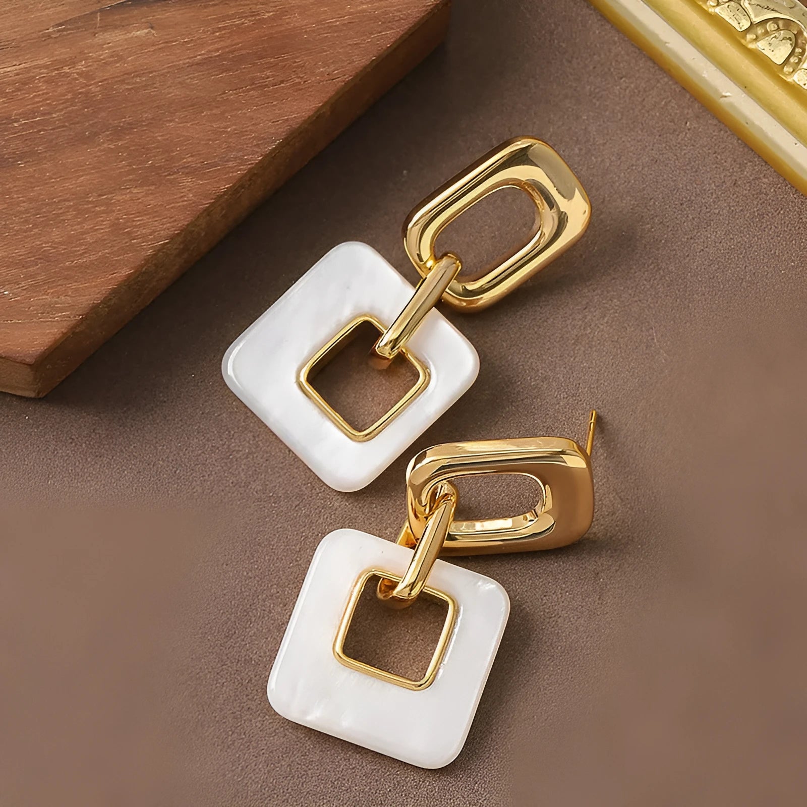 A pair of hollow geometric square copper earrings with a chamfered pattern design.