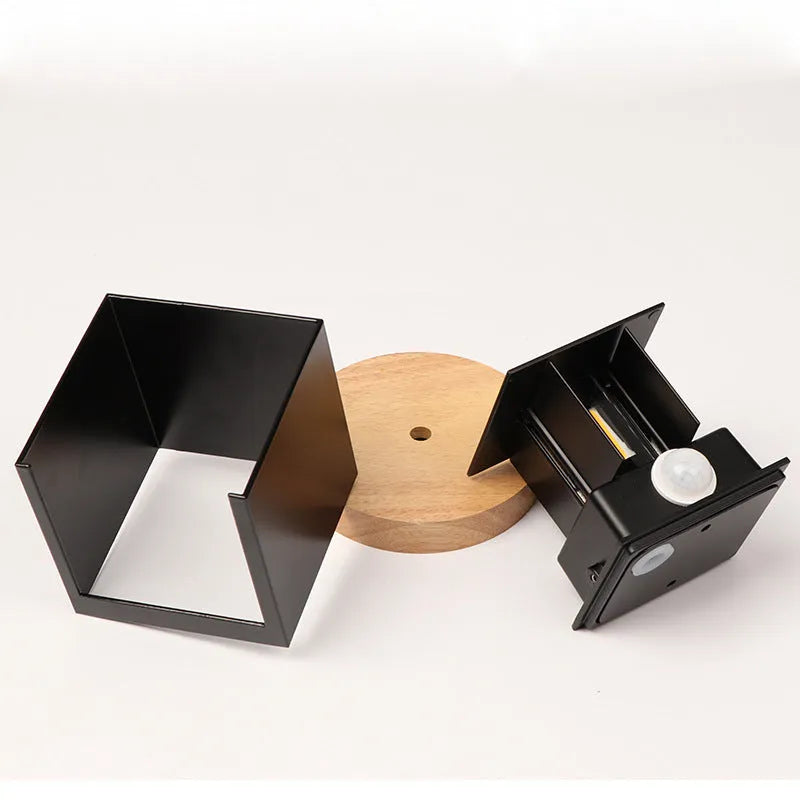 Compact black aluminium cube LED wall lamp mounted on a white wall.