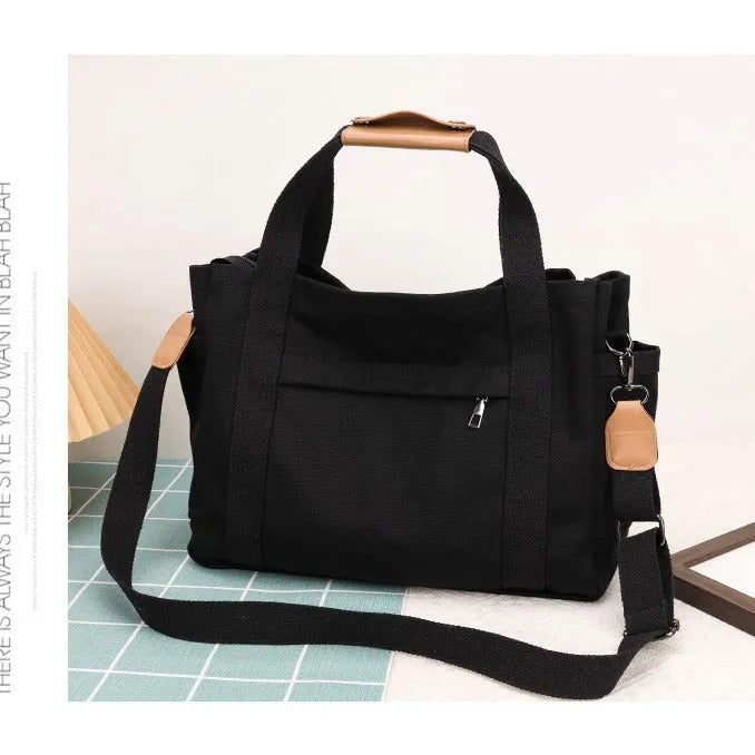 Large horizontal square canvas tote bag with cross-body strap, shown in army green colour with visible sewing lines.