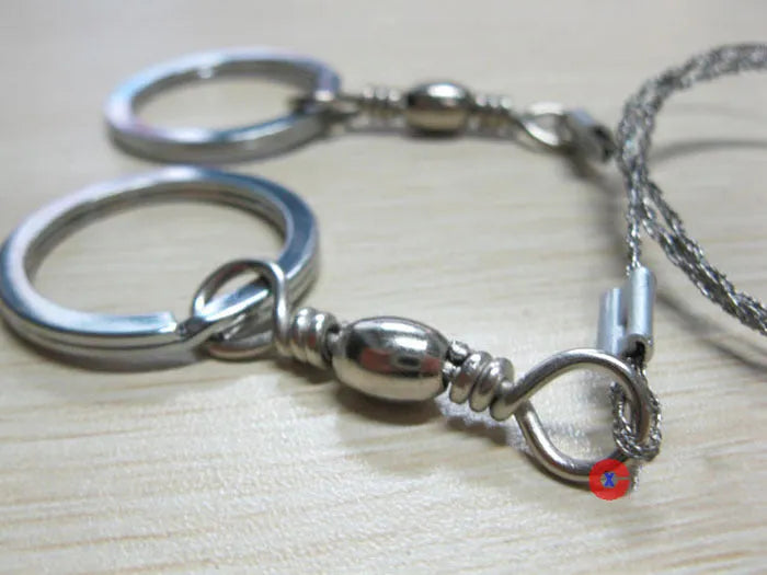 55cm stainless steel survival wire saw with pull rings and hoops on a green background.