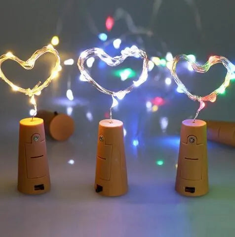 Silver wire LED string lights coiled around wine bottle with illuminated bulbs and bottle stopper fitting