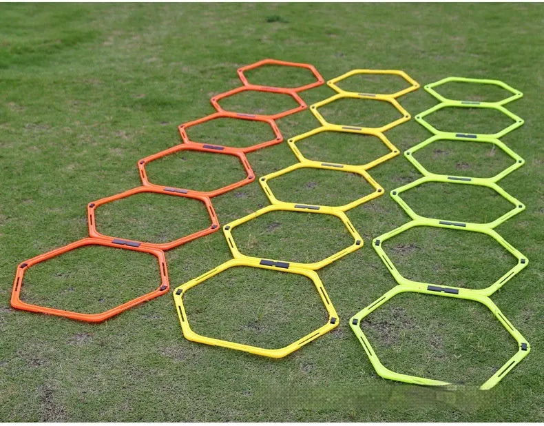 Set of six foldable yellow green and orange hexagon football agility training rings on grass.