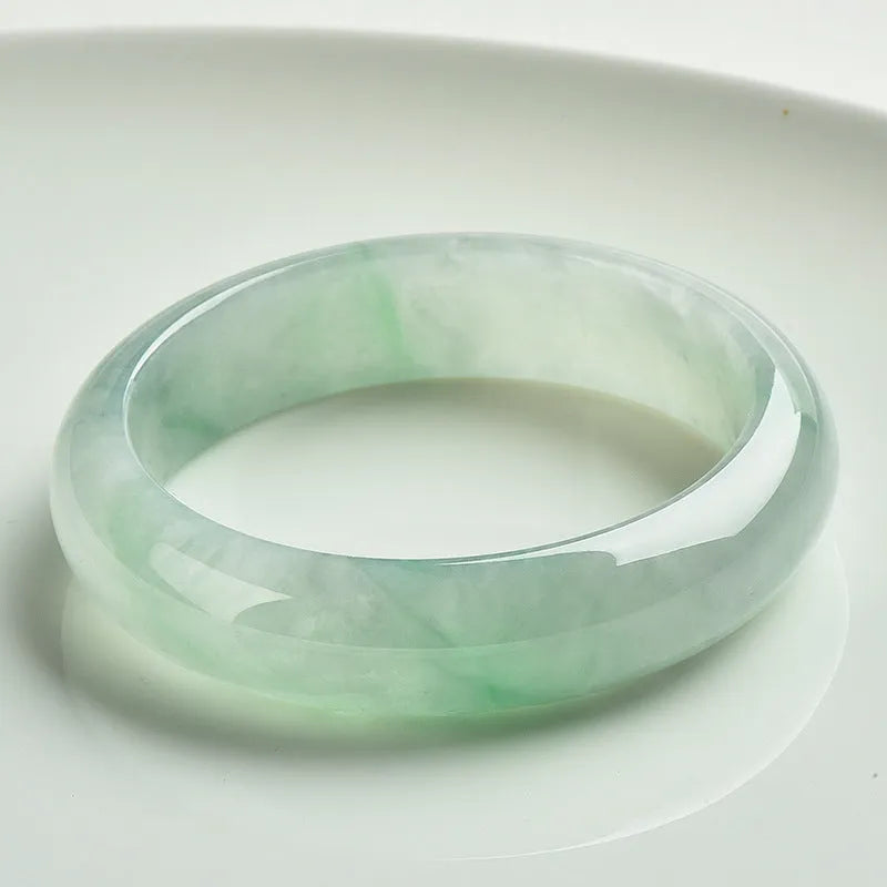 Light green polished jade bracelet in a natural style on a wrist.
