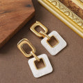 A pair of hollow geometric square copper earrings with a chamfered pattern design.