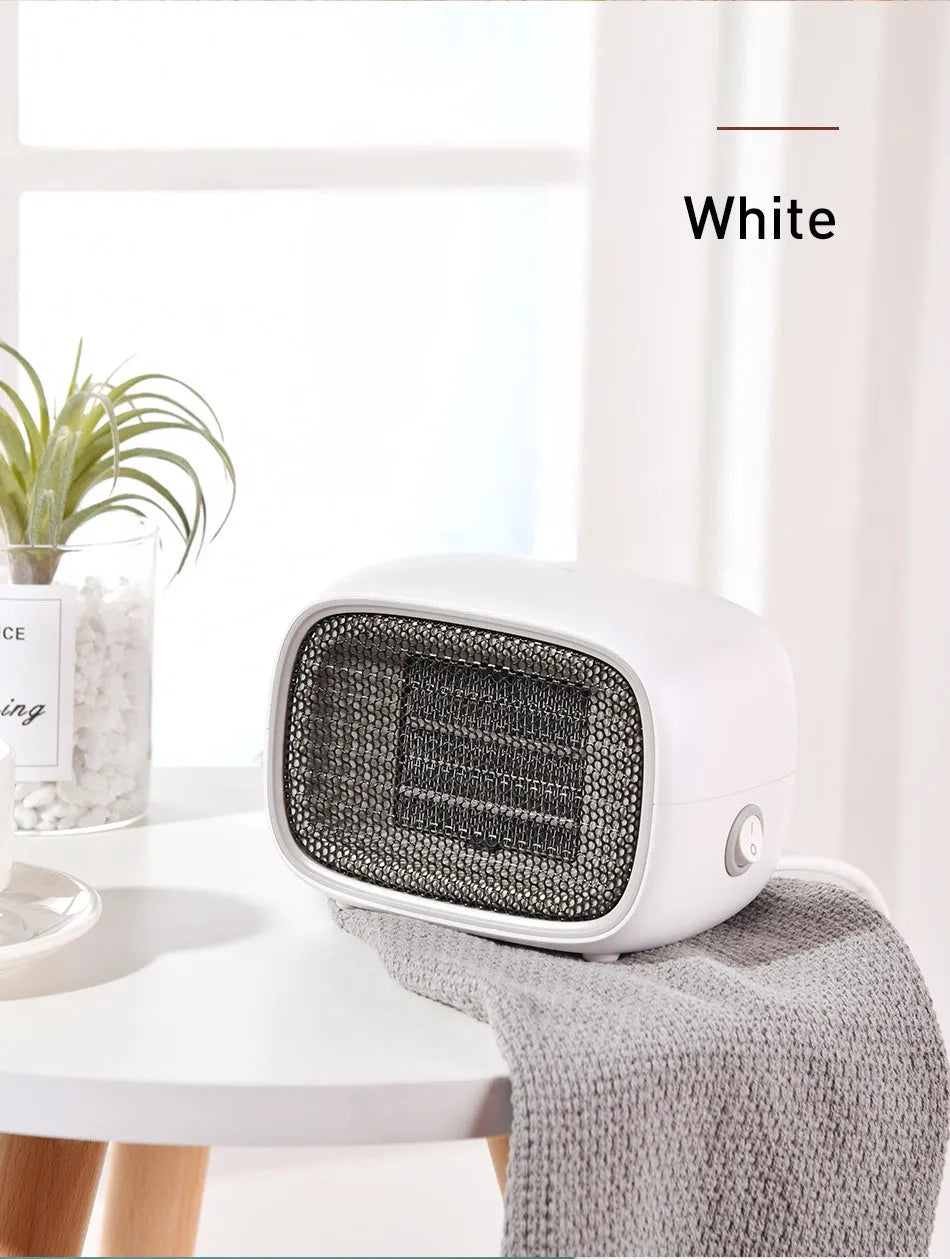 Compact green portable ceramic fan heater with metal grille, shown on a desk
