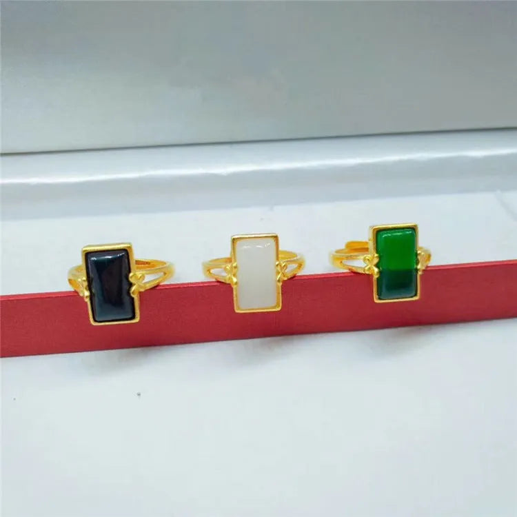 Adjustable gold-plated brass ring with a long coloured gemstone in green, white, or black.