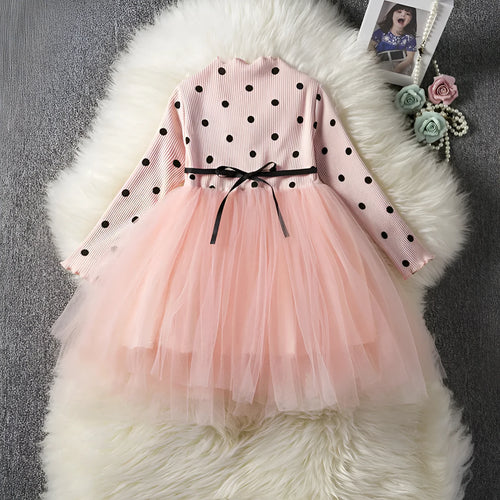 A baby girl wearing a long sleeve black tutu and lace dress for a birthday party.
