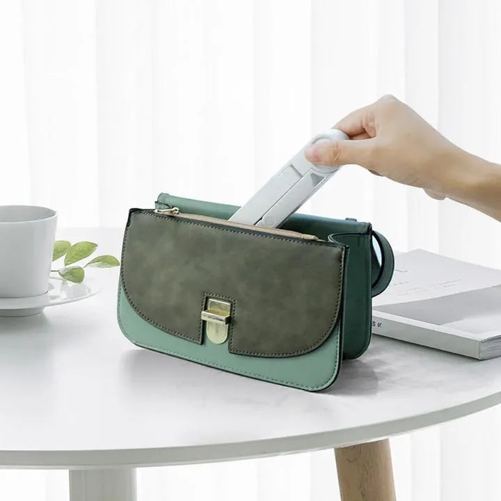 Black foldable tablet holder open in landscape mode holding a smartphone, showing side adjustment buttons.