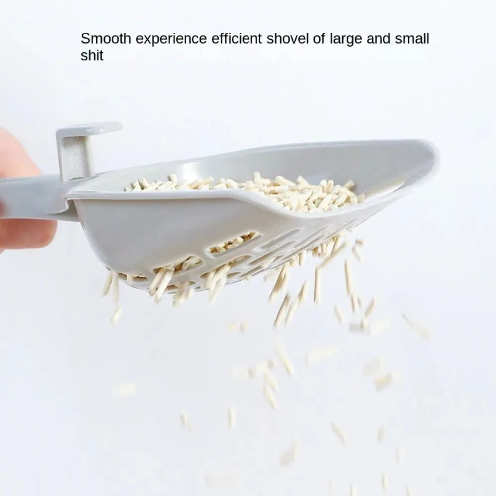 Grey plastic cat litter scoop with handle sitting upright in its integrated square base.